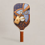 Front view of RallyStand's Grand Trunk pickleball paddle in blue, showcasing a luxury monogram pattern, brown leather graphics, and engraved gold luggage tags.